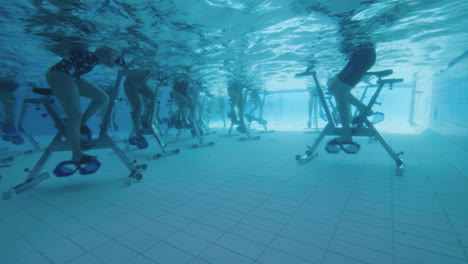 Unterwasseransicht-Von-Menschen,-Die-In-Zeitlupe-In-Einem-Schwimmbad-Aquabike-Fahren
